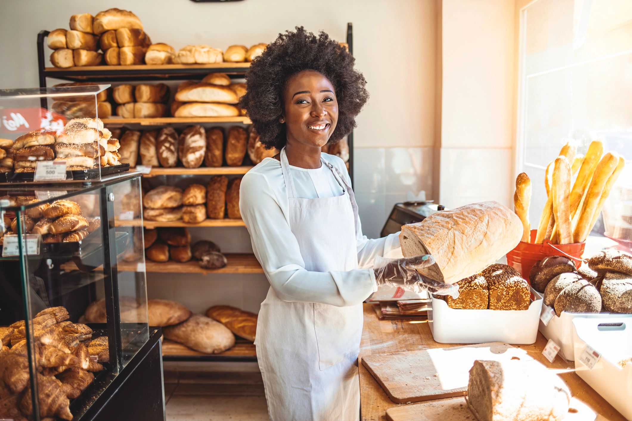 Smiling baker holding a fresh loaf in a bakery setting