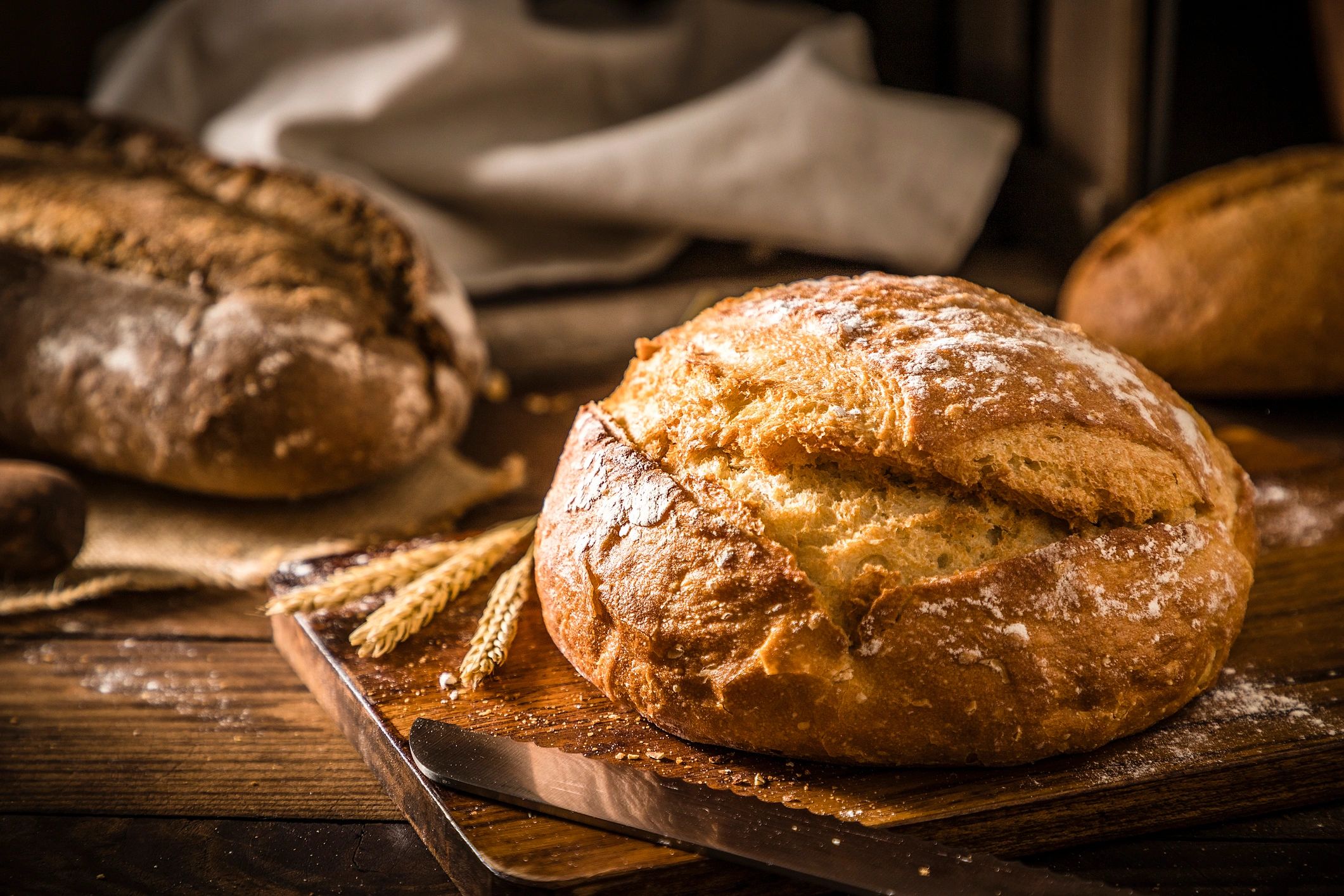 Fresh baked loaf on a rustic wooden table with a bread knife