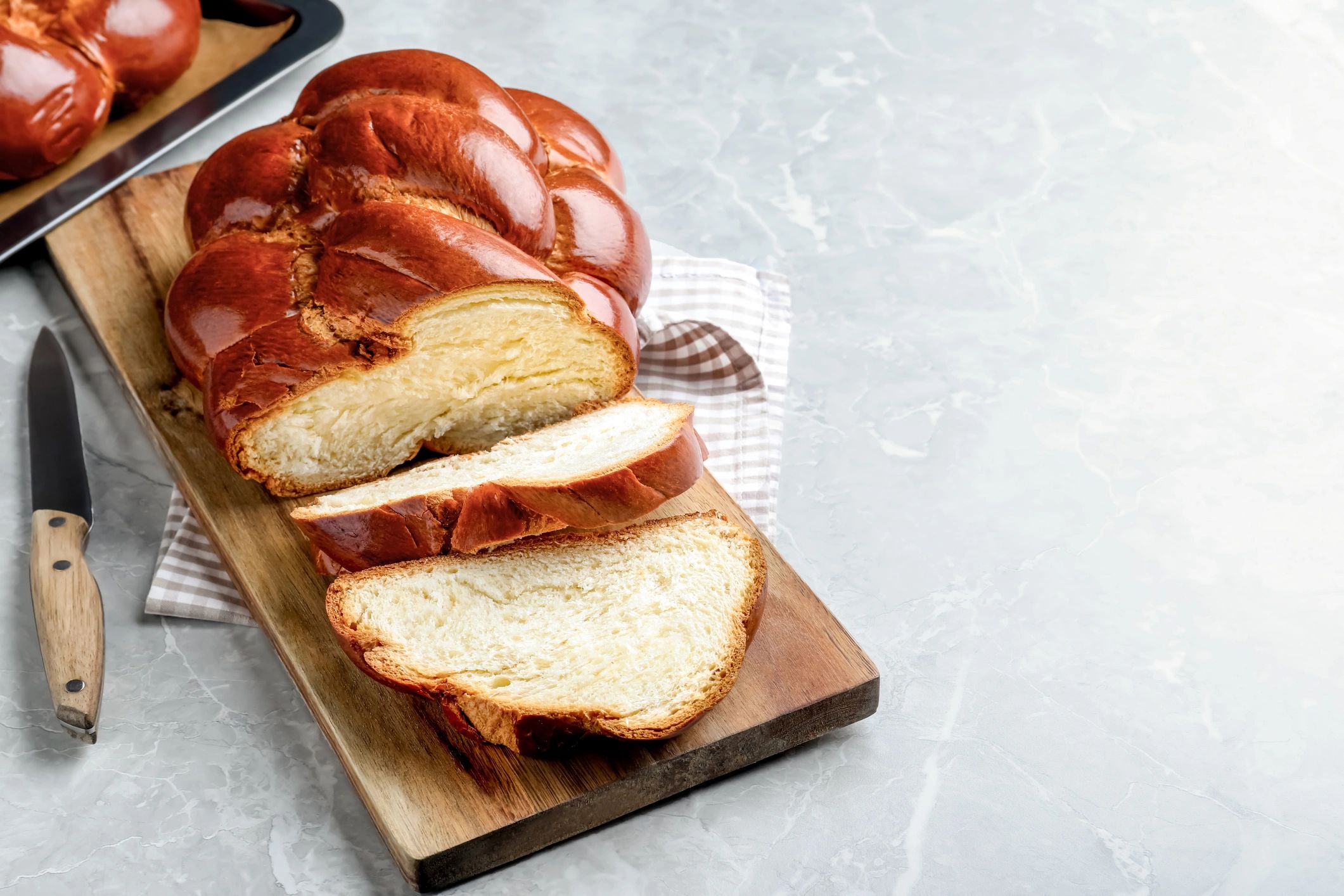 Braided challah bread sliced on a table with space for text