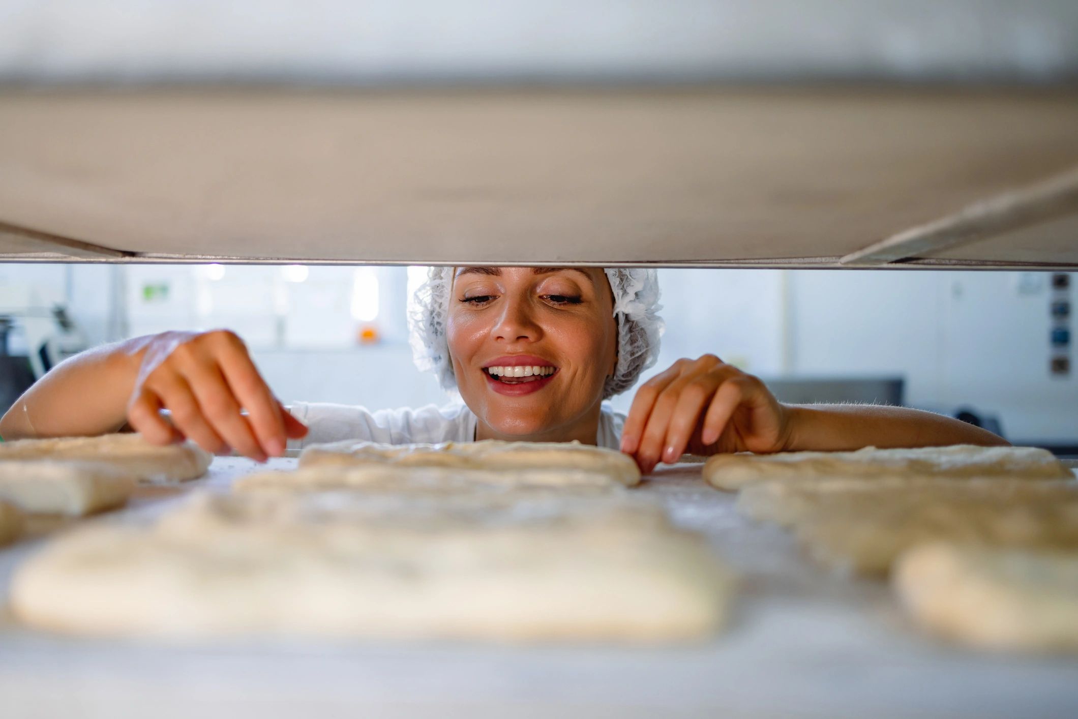Baker inspecting bread dough in a bakery