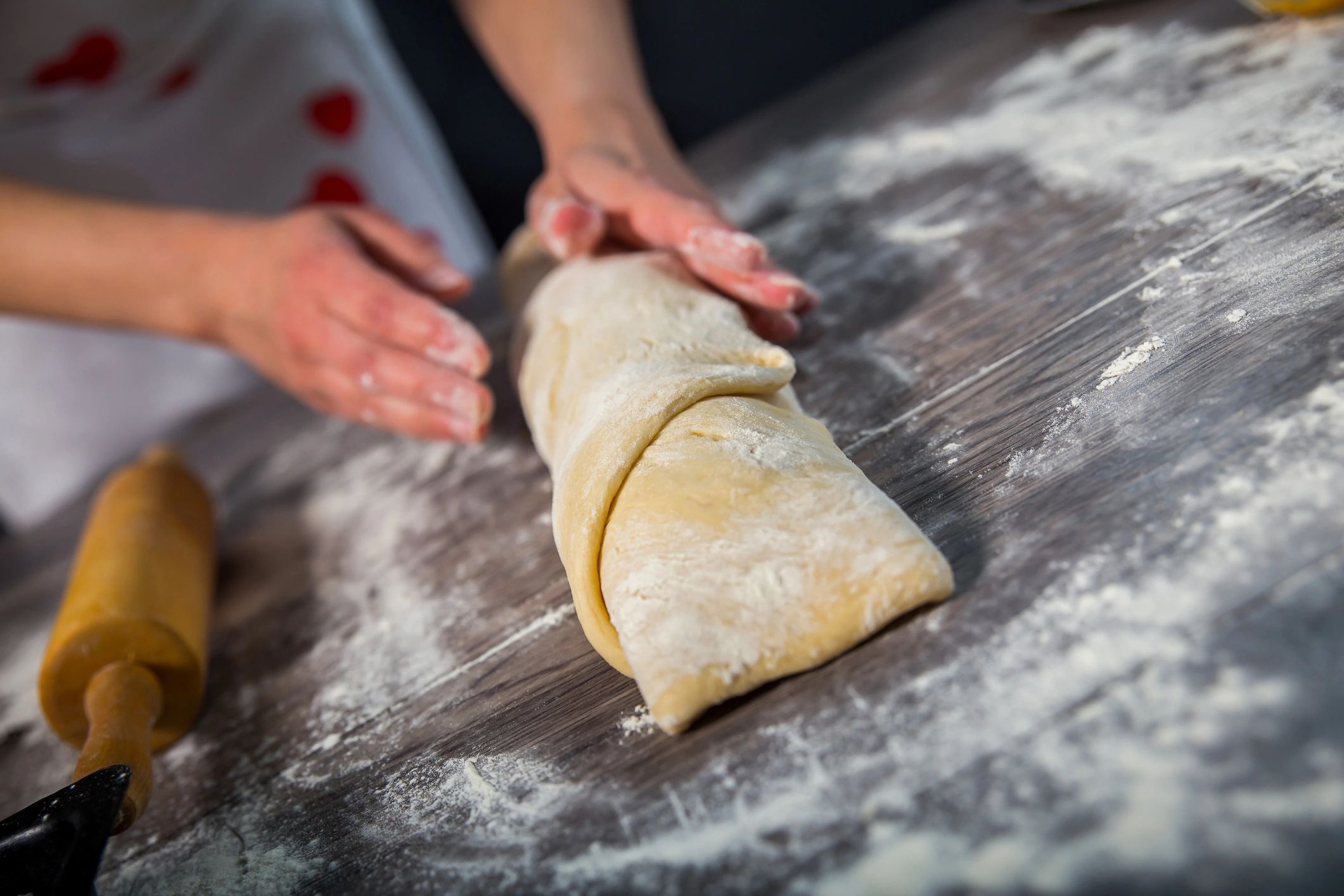 Hands working dough on a floured surface